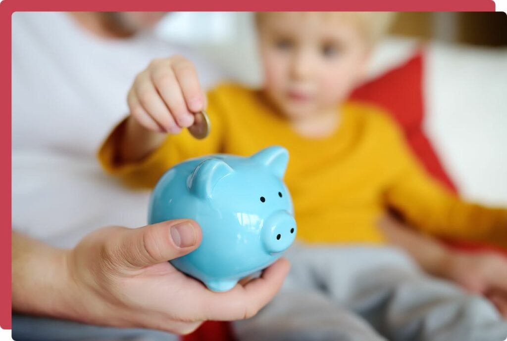 Young boy putting money into piggy bank